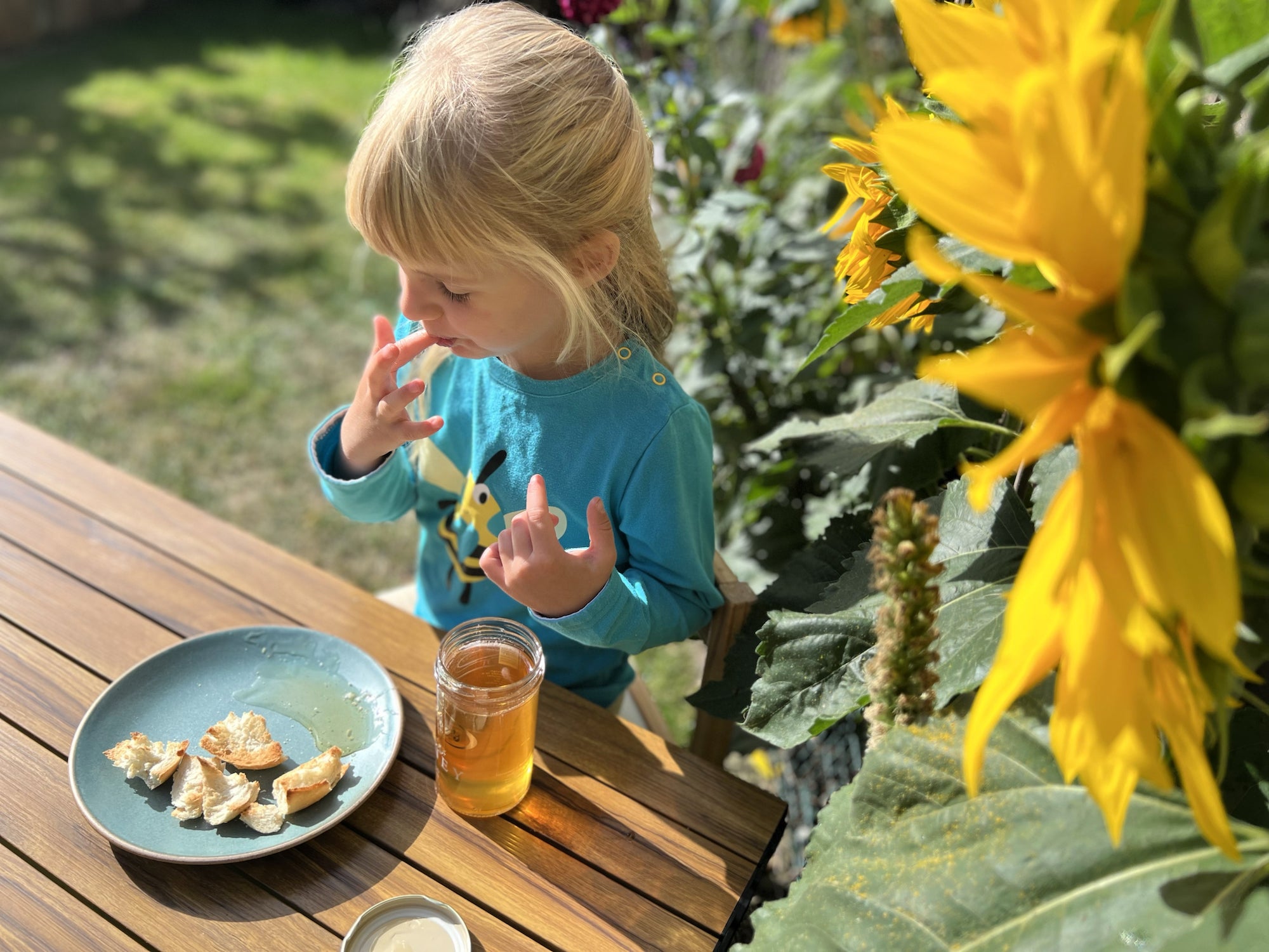 Eva Gilboy enjoying her dad's honey in the garden next to the sunflowers